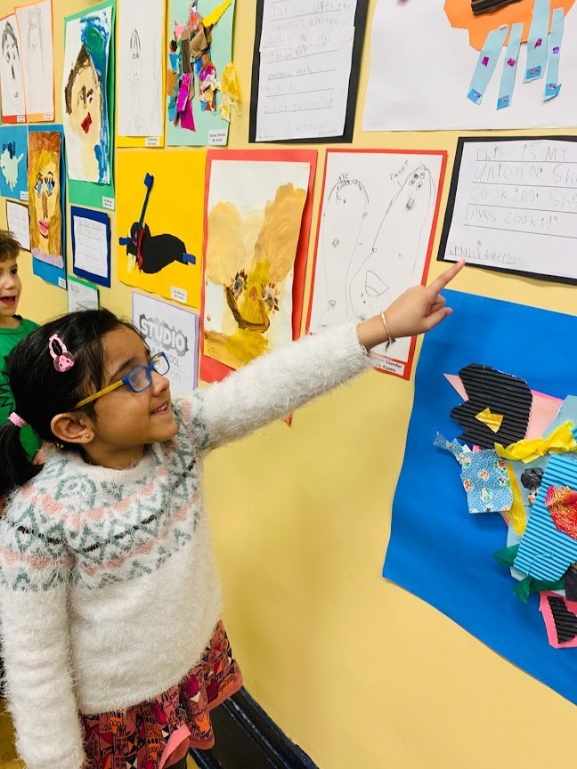 student pointing to her work on the ps8 wall
